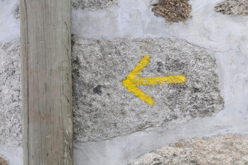 Gelber Pfeil auf Steinmauer gemalt als Wegweiser am Jakobsweg in Spanien