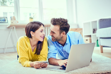 Happy couple at home paying with credit card for online shopping