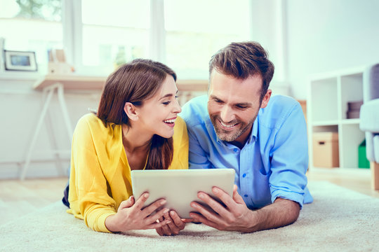 Cappy couple at home with tablet lying on the floor