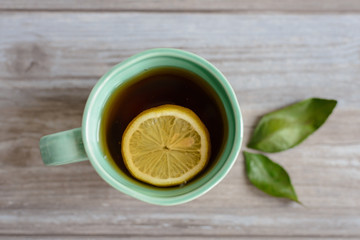 cup or mug of black tea with green leaves and lemon