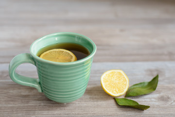 cup or mug of black tea with green leaves and lemon