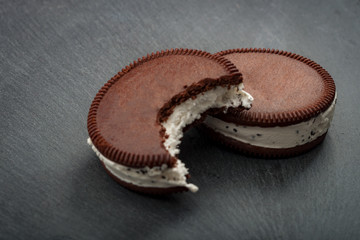 Naklejka premium Vanilla and cookie ice cream sandwich bars, one with a bite taken out of it but the bit part is not in the shot and the other one is not bitten yet and is whole