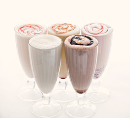five glasses of various milkshakes chocolate, strawberry and vanilla isolated on white background