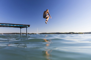 Fototapeta Junge springt vom Steg in den See obraz