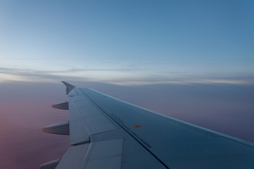 Naklejka na ściany i meble Airplane's window shot during the sunrise and cloudy sky