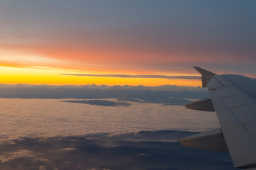 Airplane's window shot during the sunrise and cloudy sky