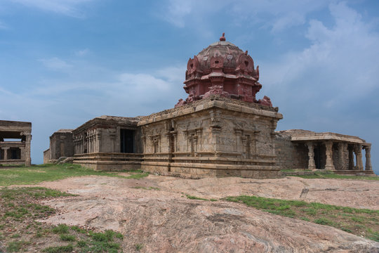 Dindigul, India - October 23, 2013: Wing with Vimanam of the abandoned ruinous Shiva Temple on the Rock in Dindigul. Red painted dome on top of brown-beige sandstone structure under blue sky.