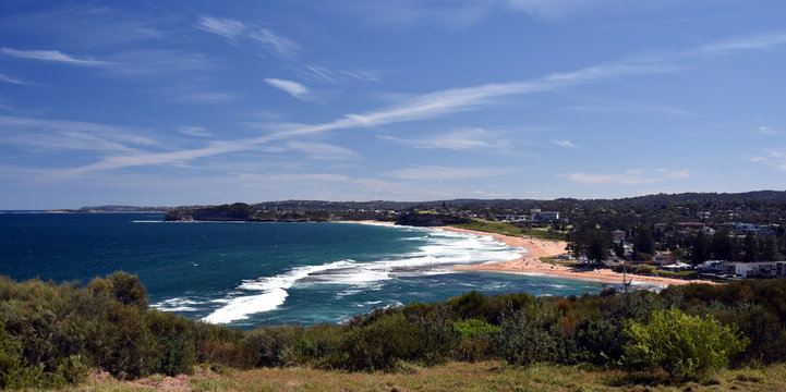 Mona Vale rock pool in a distant panoramic view from elevated lookout during high tide surfing waves and sandy beach, australia sydney northern beaches