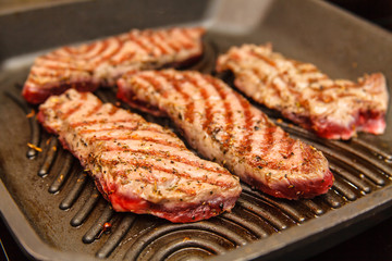 Slices of beef strip loin stir-fried in a skillet-grill, visible