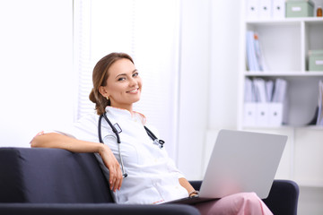 Closeup portrait of a young doctor sitting on the sofa