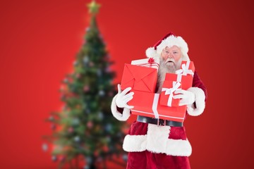 Santa claus holding stack of christmas gifts