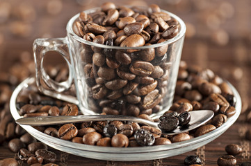 Transparent glass cup with coffee beans and a spoon