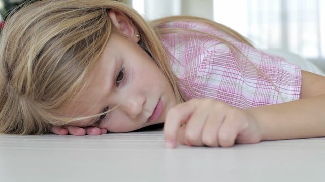Portrait of sad little girl lying on floor at home at the day time 