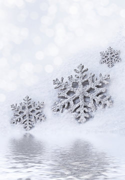 Glass toy snowflake on snow background.