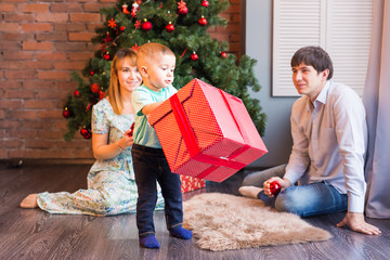 Obraz na płótnie Canvas Cheerful boy holding gift box near christmas tree