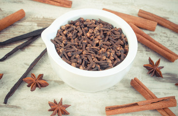 Vintage photo, Fragrant cloves in mortar and spices on rustic board