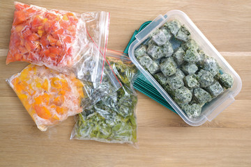 Frozen vegetables on cutting board and plastic bags. top view