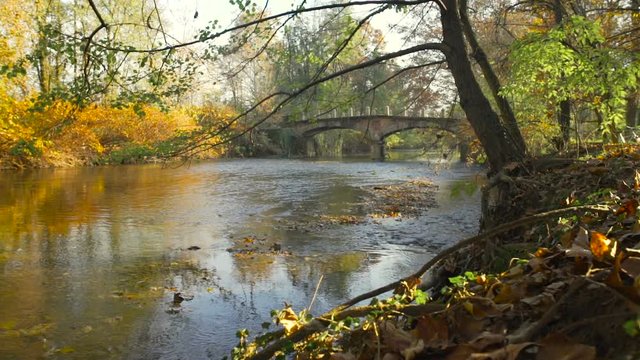 Old bridge on a quiet river and trees in autumn