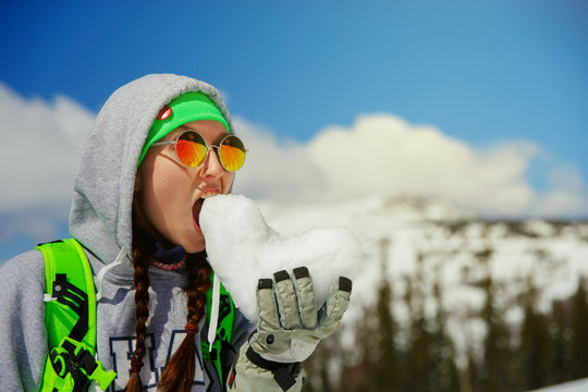 portrait of young snowboarder girl With snow heart in hands