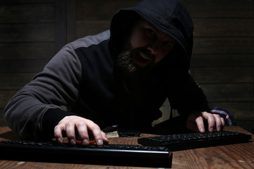 hacker in the black hood in a room with wooden walls