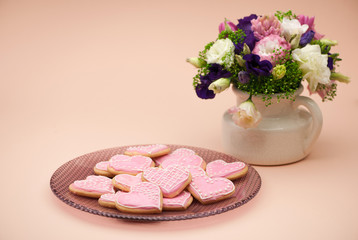pink cookies in the shape of hearts on a plate and flowers on Valentine's Day