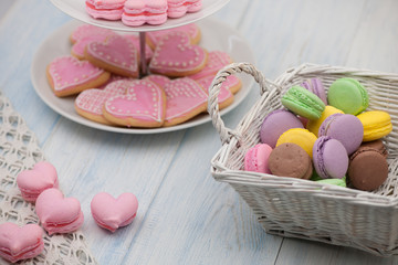 pink cookies in the shape of hearts on a plate and pastries in a wicker basket on the wooden boards on the day of valentine