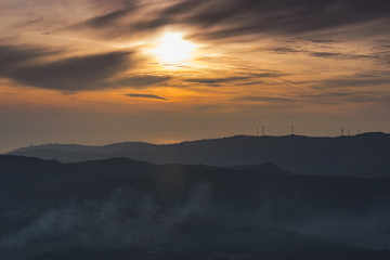 wind farm on the top of a mountain at sunset
