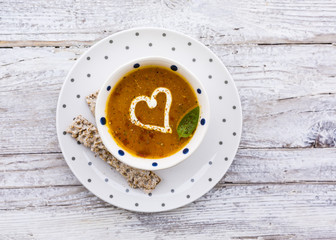 Creamy pumpkin soup with herbs and cream in the shape of hearts. Vegetarian food.