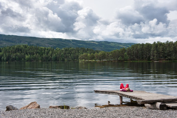 Girl lying on a pier on the lake shore, Norway