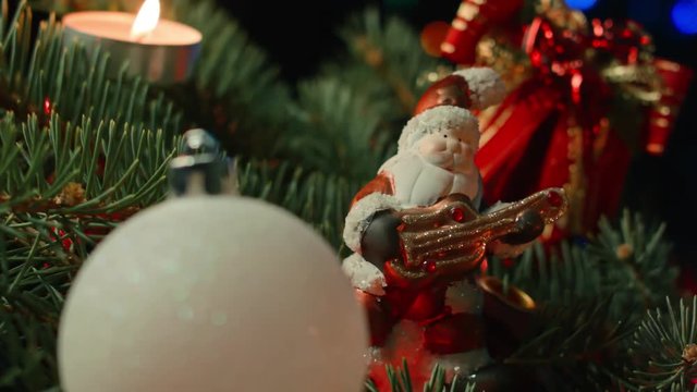 toy Santa on the Christmas tree with Christmas balls and candle