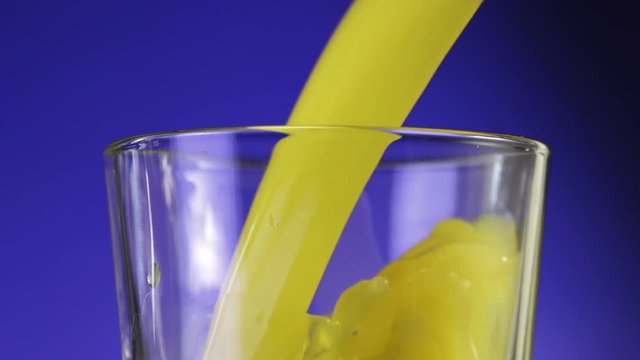 Orange juice pouring in glass on color background