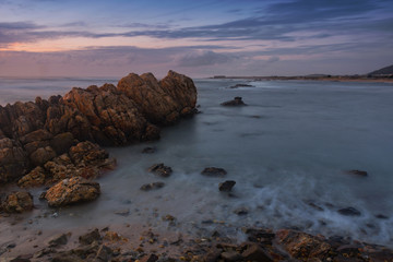 sunset at beach with rocks and sky with clouds