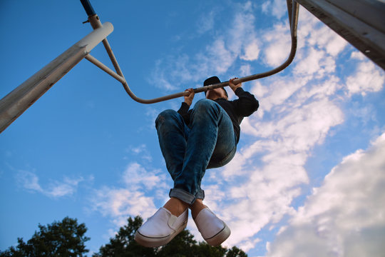 A Young Woman Is Doing Pull Ups In The Park