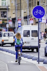 Naklejka premium Young woman ride bicycle on bicycle lane. Bicycle lane sign. Bicycle. Pedestrian.