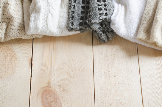 Cozy and soft winter background. Warm knitted clothes on a wooden background.