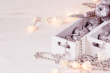 Christmas soft silver apples and lights burning in boxes  on a wooden white  background. New Year postcard. Xmas background.