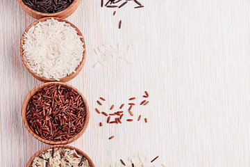 Red, black and white rice close-up in wood bowls on beige fabric. Rice texture background.