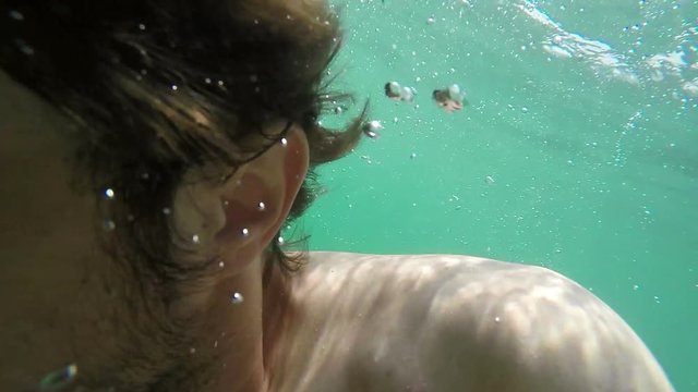 Adult caucasian male dives in sea water, slow motion