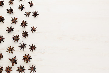 Fototapeta na wymiar Anise stars spice pattern on white wood background. Christmas decorative frame. Top view.