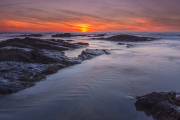 sunset at beach with rocks and clouds