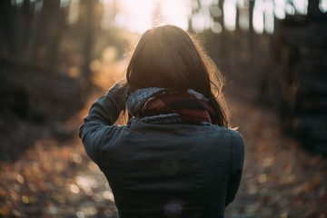 Close up back view of woman in forest watching sunset