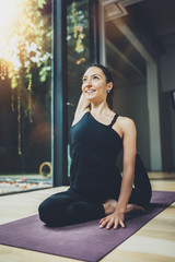Portrait of happy young woman practicing yoga indoor. Beautiful girl practice relaxation asana in class.Calmness and relax, female happiness concept.Horizontal, blurred background, flares.