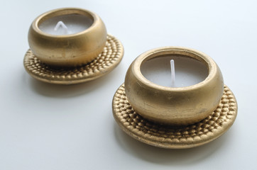 Two decorative candles in gold color on a light background