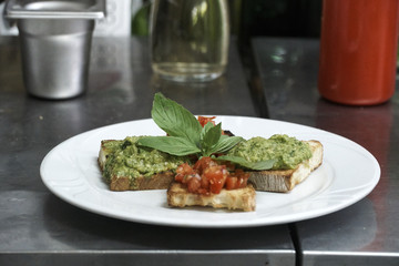 Plate full of bruschetta bread with tomato and pesto sauce