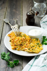 Pancakes with cabbage and spinach on a white ceramic plate on old wooden background. Rustic style. Selective focus.