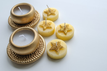 Obraz na płótnie Canvas Two decorative candles in gold color and four candles with star pattern on a light background 