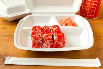 Assembling Japanese food in white disposable container on a wood