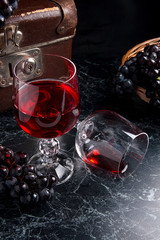 Glass of red wine on dark marble background. Cluster of blue gra