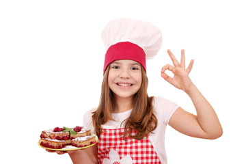 happy little girl cook with homemade cake and ok hand sign