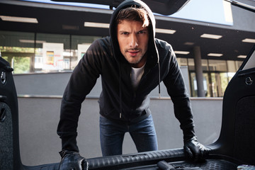 Criminal young man standing and looking at car trunk © Drobot Dean
